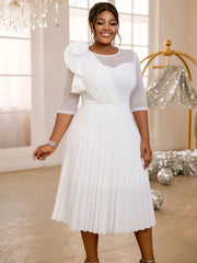 A woman wears a white knee-length A-line dress featuring a pleated skirt, tulle sleeves, and ruffles.