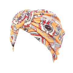 A yellow turban hat featuring a bohemian paisley print and a knotted front detail.