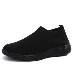 A black slip-on sneaker with a textured knit upper and a thick, ribbed rubber sole.