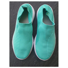 A pair of teal slip-on sneakers with a textured knit upper and white flat soles.