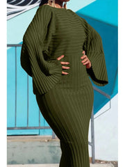 A woman wears an olive green, ribbed knit midi dress with batwing sleeves and a round neckline.