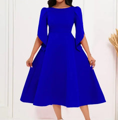 A woman wears a solid royal blue A-line midi dress with a round neckline and petal sleeves.