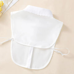 A white detachable fake collar with a scalloped edge and adjustable side straps.