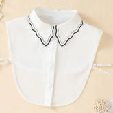 A white chiffon detachable collar featuring a scalloped edge with black trim and button detailing.