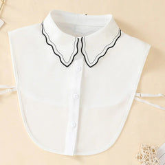 A white chiffon detachable collar featuring a scalloped edge with black trim and button detailing.