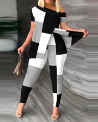 A woman wears a black, white, and gray color-blocked two-piece set with a sloped collar top.