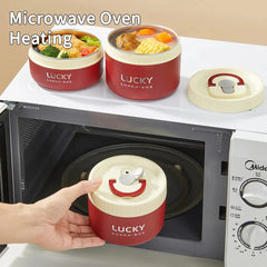 A person places a round, red and cream-colored stainless steel lunch box into a microwave.