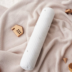 A white cylindrical baby pillow with a star and moon pattern resting on a beige knit blanket.