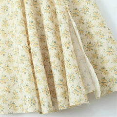 A close-up view of a cream-colored A-line dress featuring a delicate yellow floral print.