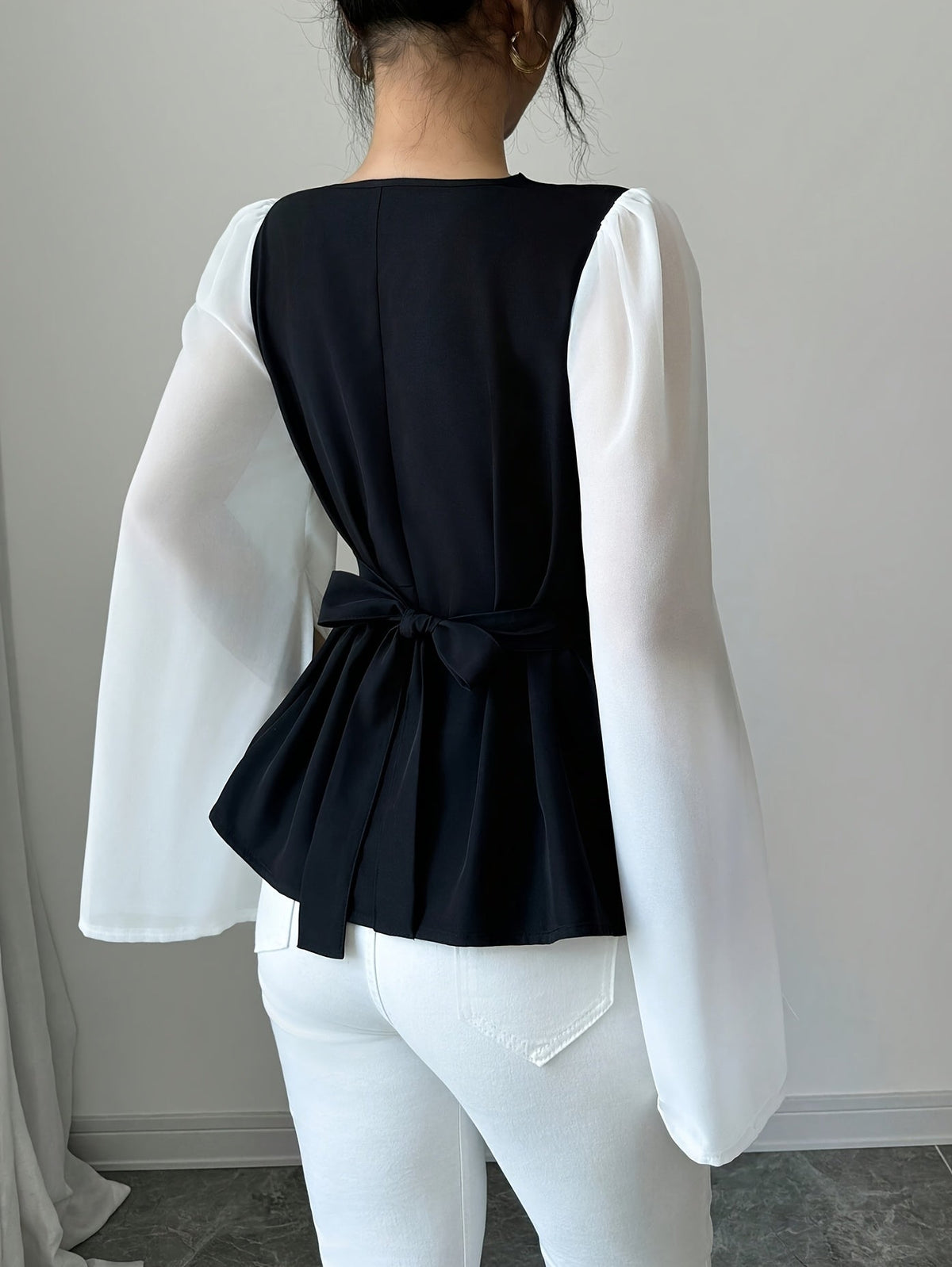 SHOWLU Women's black and white pleated asymmetrical long sleeve blouse with stylish design and flowing fabric.