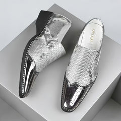 A pair of silver snake-patterned slip-on shoes with metallic brogue toes and chunky heels.