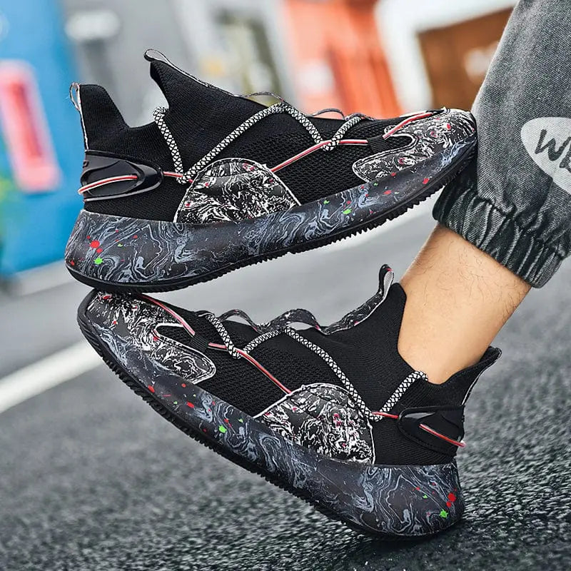 A person wears 2022 Top Sale Fashion Sneaker Footwear—breathable, recycled men’s running shoes in black with a marbled black, white, and red sole. The sneakers feature rope-style laces, textured details, and a standout futuristic design.