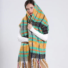 A woman wears a long, thick, plaid cashmere scarf in yellow, green, and orange with fringe ends.