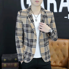 A man wears a slim-fit, single-breasted tan and black plaid blazer over a white t-shirt.
