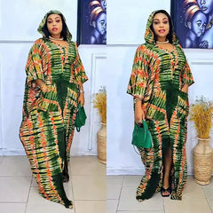 A woman wears a green and orange patterned hooded maxi kaftan dress with side pockets.