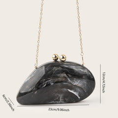 An elegant black and white marbled acrylic clutch with a gold chain strap and magnetic bead closure.