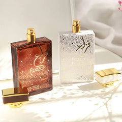 Two rectangular perfume bottles labeled Fazza, one in dark brown and one in white, with gold caps.
