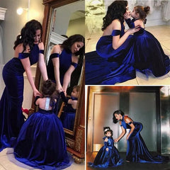 A woman and young girl wear matching Backless Velvet Flower Girls Dresses—off-the-shoulder, royal blue ball gowns—posing together by a mirror and on the floor. The girl's dress is perfect for a flower girl or first communion look.