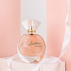 A round glass bottle of Boitown perfume filled with shimmering peach-colored liquid.