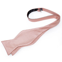 A pink self-tie bow tie with a textured pattern laid flat on a white background.