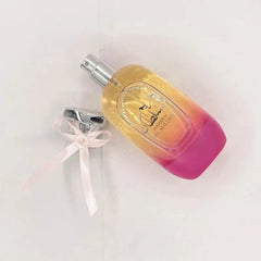 A bottle of Hareem Al Sultan perfume with an ombre yellow to pink glass and a pink bow cap.