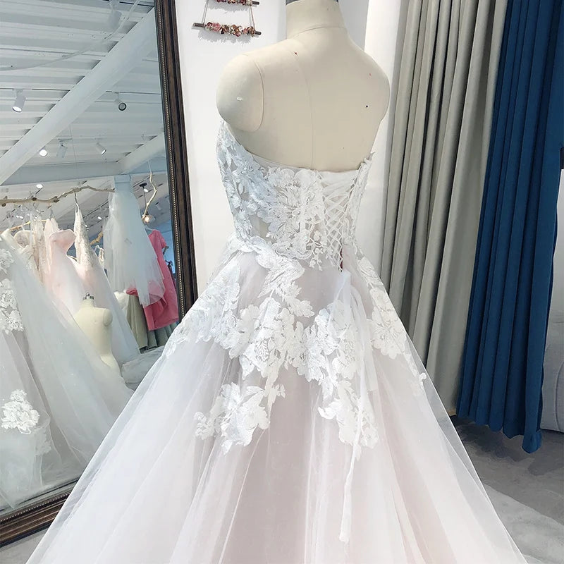 Elegant strapless tulle bridal gown with lace appliqué, A-line silhouette, sweetheart neckline, court train, perfect for weddings.