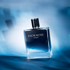 A glass bottle of Enormous Homme cologne with a blue gradient finish on a blue background.