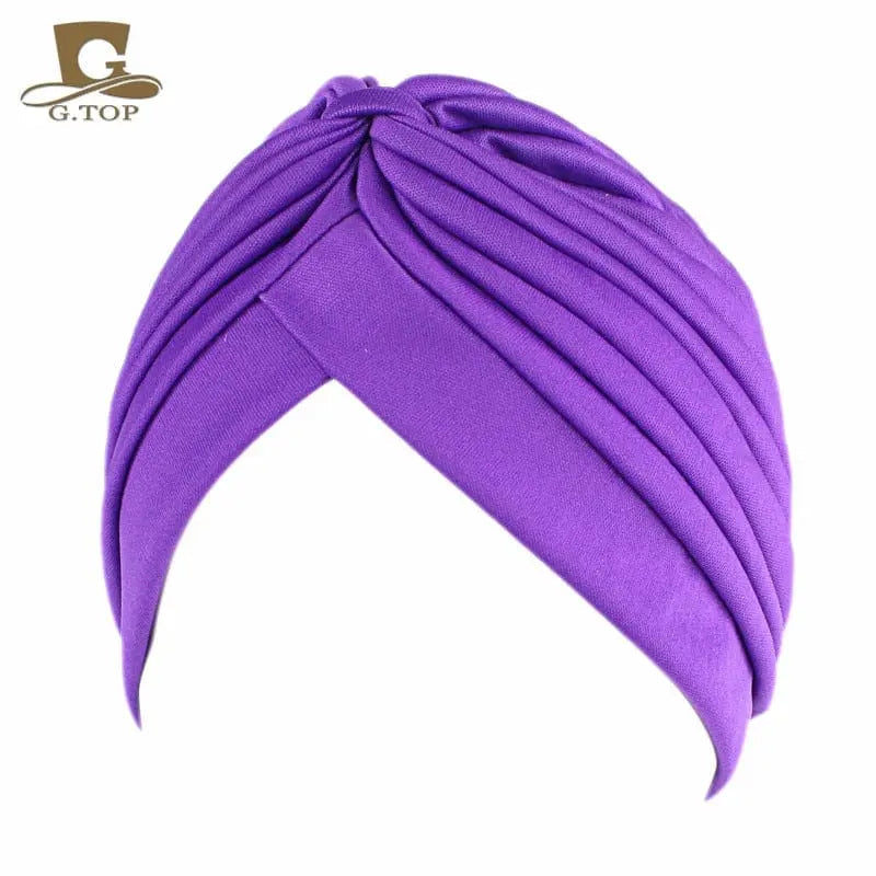 Stretchy women's turban cap with twisted pleats, shown in assorted colors, designed as a chemo headwrap or beanie hat for women and girls.