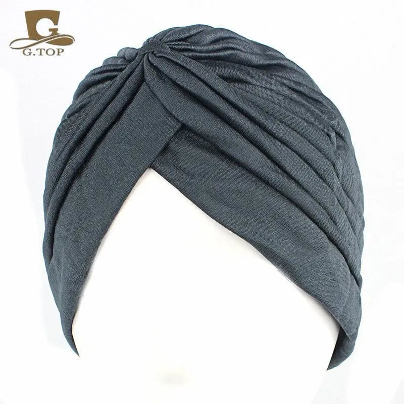 Stretchy women's turban cap with twisted pleated design, in assorted colors, suitable as a chemo beanie or stylish headwrap.