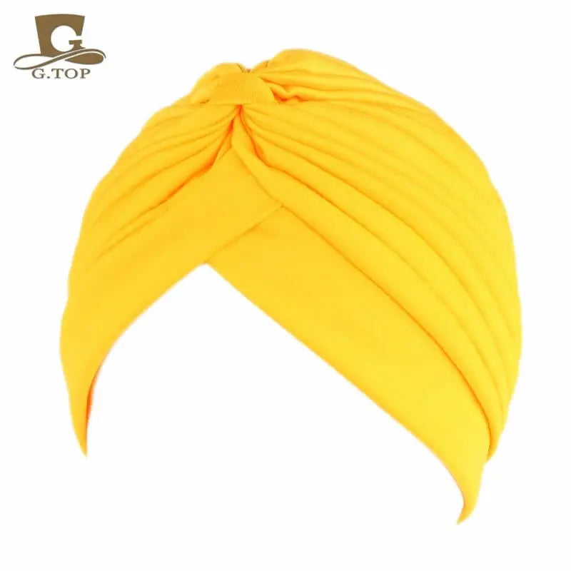 Stretchy women's turban cap with twisted pleated design in assorted colors, styled as a chemo head wrap and beanie hat.