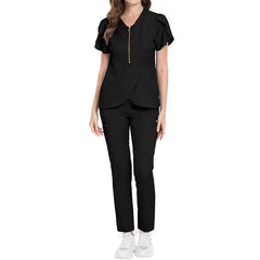 A woman wears a black nursing scrub set featuring a zip-front top with flutter sleeves.