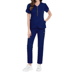 A woman wears a navy blue nursing scrub set featuring a zippered top and matching pants.
