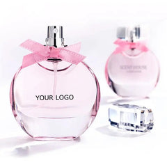 The Perfume Customize Luxury Fragrance OEM Perfume features a clear round bottle with a pink bow, shown next to a similar bottle and cap on a white background—an elegant design ideal for showcasing your favorite scent.