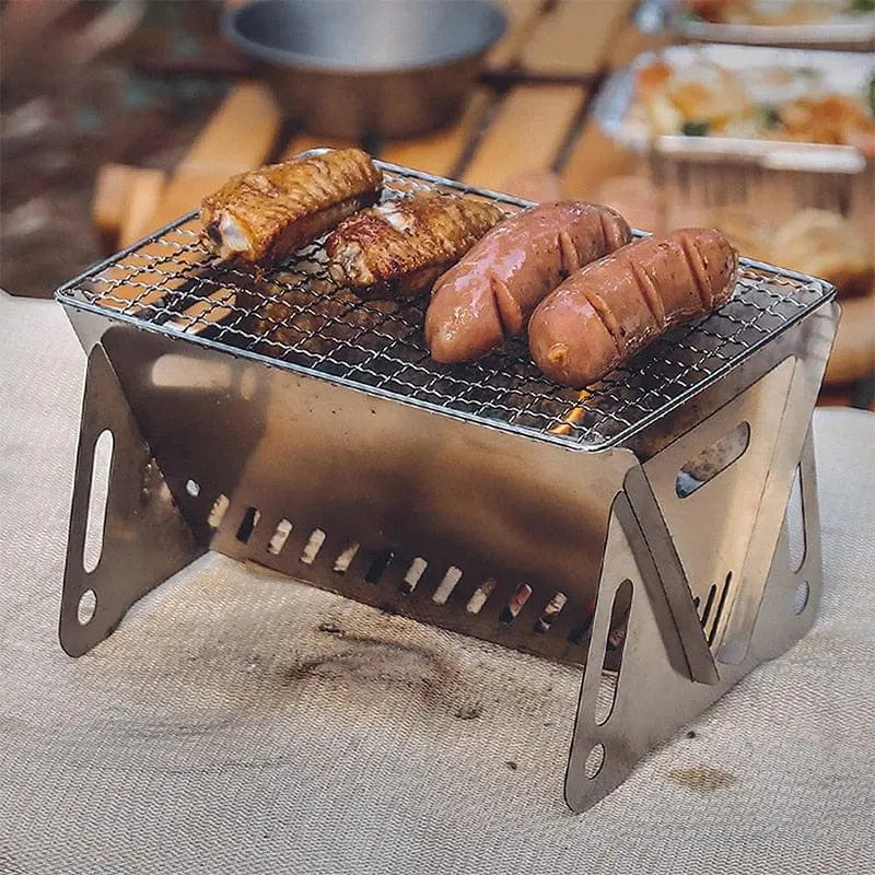 Portable FLYMUYU stainless steel folding BBQ grill for camping, featuring a compact design with a grilling rack and firewood stove.