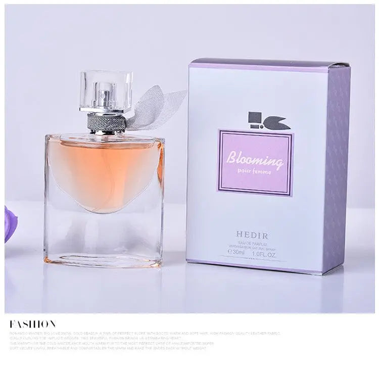 A 30ml bottle of Blooming pour femme perfume next to its purple and white box.