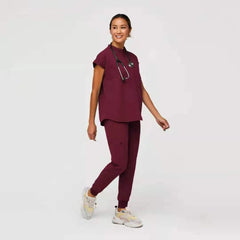 A woman wears a burgundy medical scrub set with a short-sleeved top and matching jogger pants.