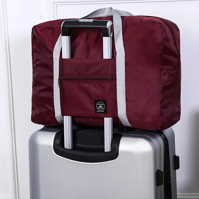 Red, navy, and green multifunctional folding travel bag with large capacity, waterproof design, single shoulder handle, ideal for luggage.