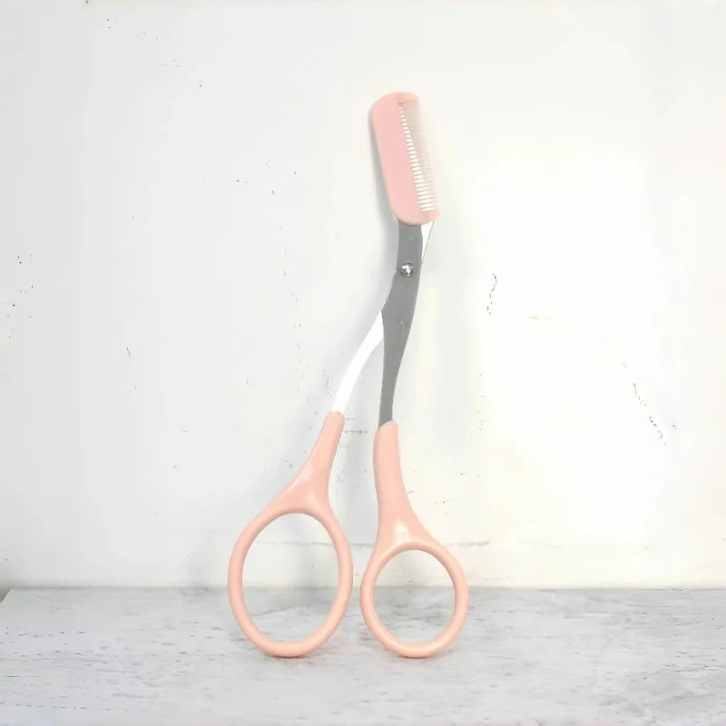 Pink stainless steel eyebrow trimming scissors with built-in comb for precise grooming and shaping of eyebrows.