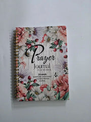 A spiral-bound prayer journal for women featuring a floral design on a wood-grain background.