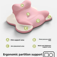 A pink ergonomic prone position pillow with labeled sections for chin, chest, arm, and waist support.