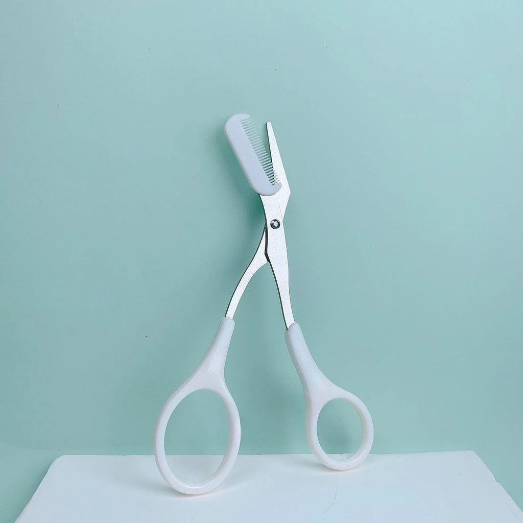 Pink stainless steel eyebrow trimming scissors with built-in comb for precise grooming and shaping of eyebrows.