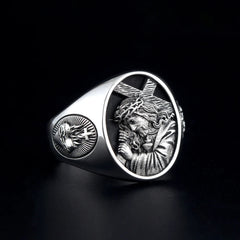 A silver ring featuring an embossed image of Jesus carrying the cross and a sacred heart emblem.