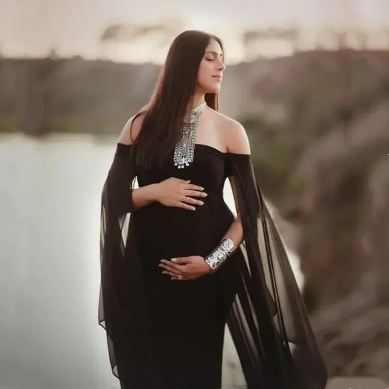 Off-shoulder maternity dress for pregnancy photography, fluttering maxi gown for women, shown in a photo shoot setting.