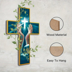A wooden cross wall hanging featuring an image of hands raised toward a glowing cross.