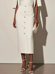 A woman wears a white midi sheath dress with decorative buttons and split sleeves.