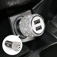 A dual USB car charger decorated with rhinestones, shown plugged into a vehicle power outlet.