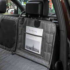 A grey quilted dog car seat cover with a mesh window and a storage pocket installed in a vehicle.