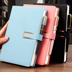 Three A5 leather notebooks in light blue, pink, and black, each featuring a matching pen holder.