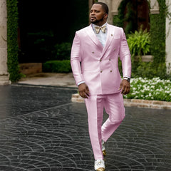 A man wears a light pink double-breasted suit with a peaked lapel and a gold bow tie.