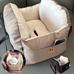A tan pet car seat with a safety tether and side pocket, shown with a small dog inside.